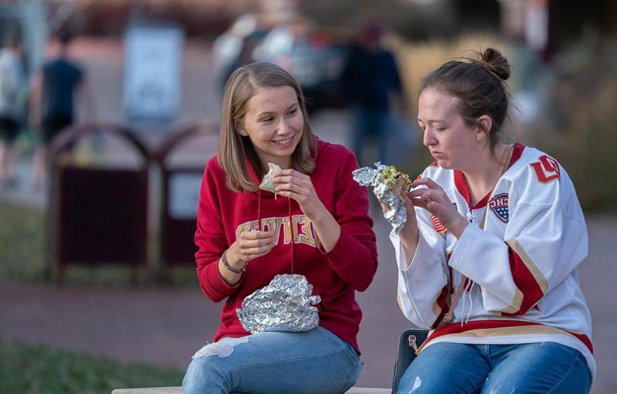 two students in DU gear eating outside